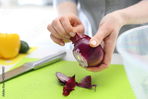 Obieranie cebuli. Kobieta kroi czerwona cebulę