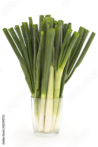 Young spring green onion in glass isolated on white background