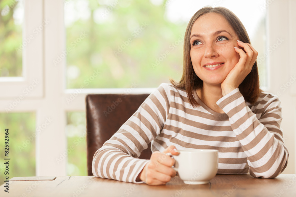Smiling brunette woman having a cup of coffee while sitting and Smiling brunette woman having a cup of coffee while sitting and
