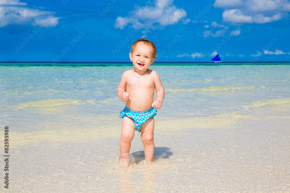 A little kid in a large white straw hat having fun on a beach A little kid in a large white straw hat having fun on a beach