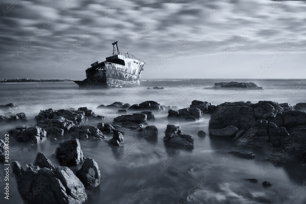 Old shipwreck long exposure on rocks at sunset artistic conversi