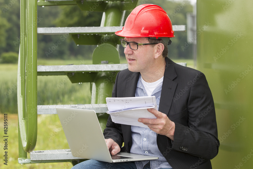Architect Holding Blueprints While Using Laptop Architect Holding Blueprints While Using Laptop