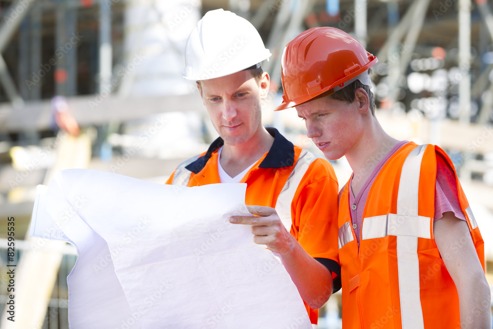 Architects Wearing Protective Wear While Analyzing Blueprint