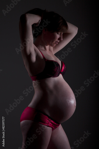 Schwangere Frau in Wäsche im Schatten Porträt