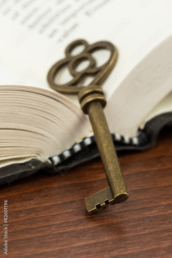Antique key on opened book page Antique key on opened book page