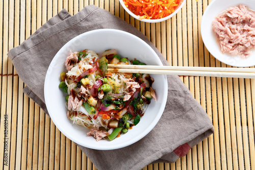 Rice noodles with tuna, peas and onions in a white bowl