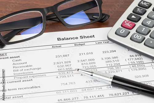 Balance sheet financial report with pen, glasses, and calculator