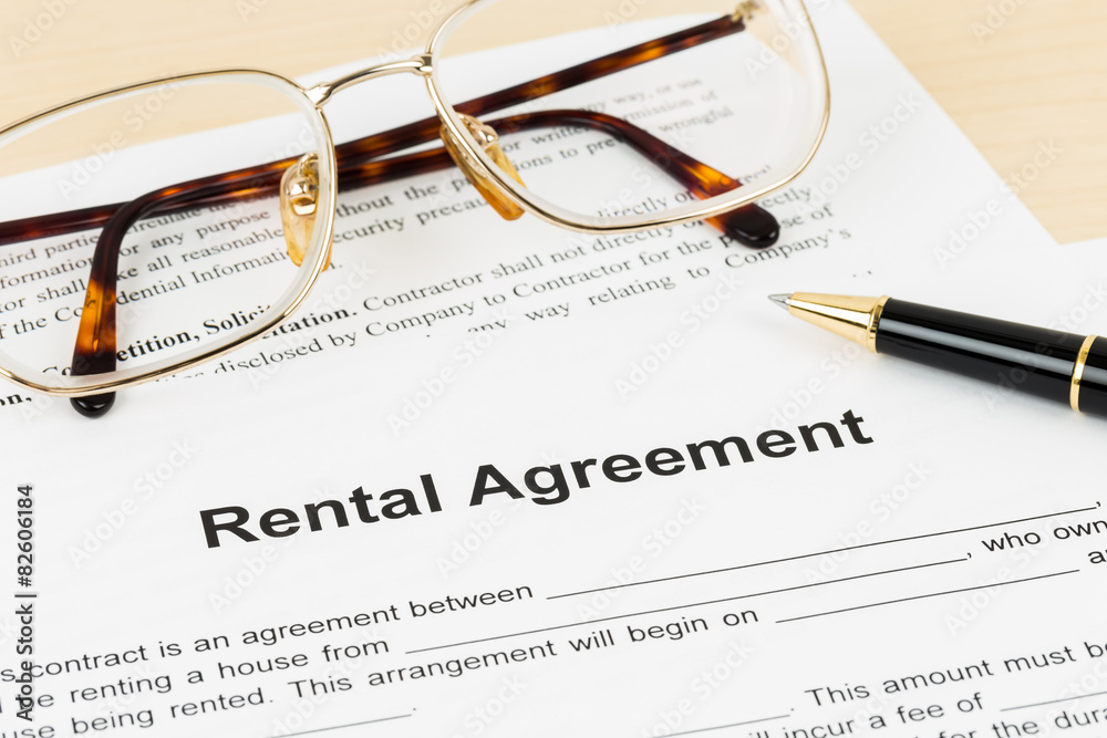 Rental agreement document with glasses and pen, document is mock Rental agreement document with glasses and pen, document is mock