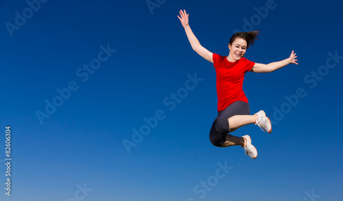 Teenage girl jumping, running outdoor against blue sky