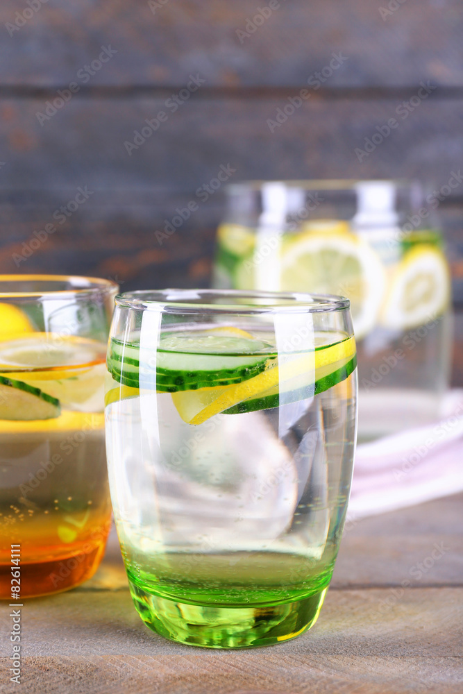 Fresh water with lemon and cucumber in glassware on wooden background Fresh water with lemon and cucumber in glassware on wooden background