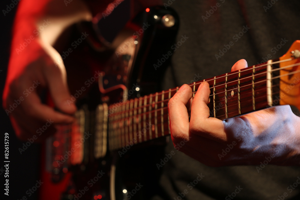 Fototapeta premium Young man playing on electric guitar close up