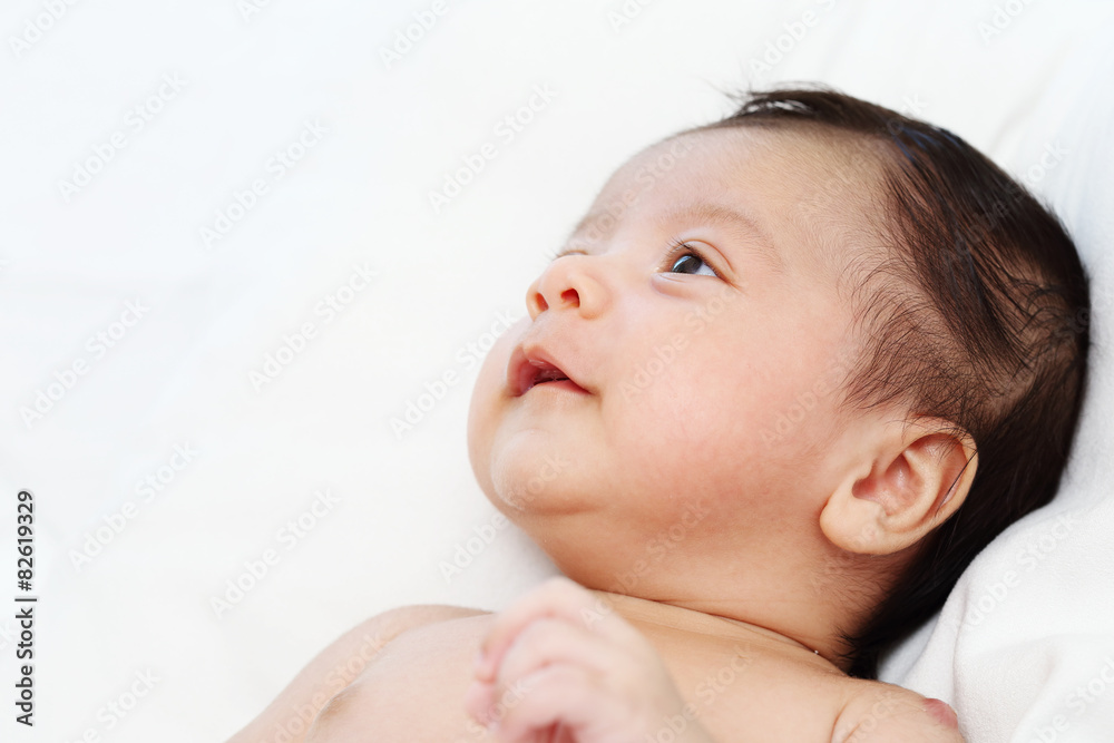 Cute baby boy is happy and looking someone on white bed Cute baby boy is happy and looking someone on white bed