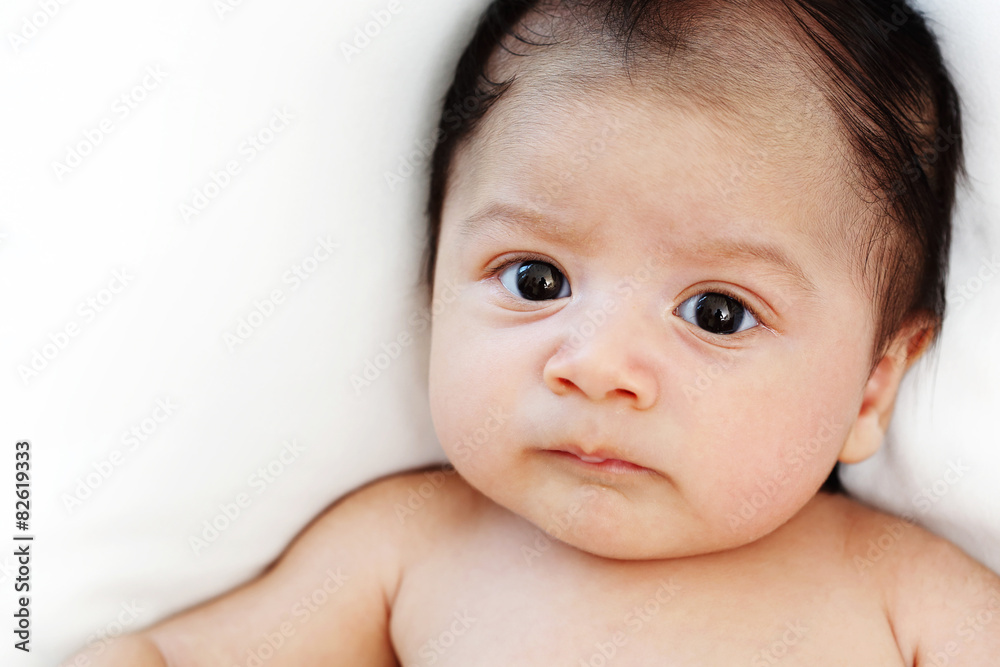 Cute baby boy is happy and looking someone on white bed Cute baby boy is happy and looking someone on white bed