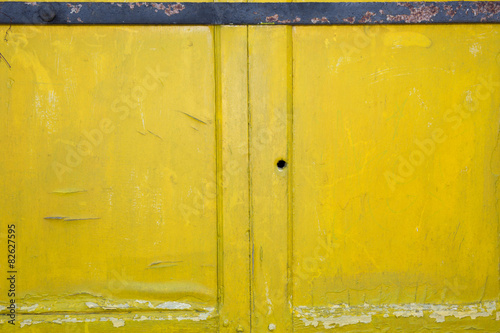 Background of yellow, peeling paint on an old wooden wall