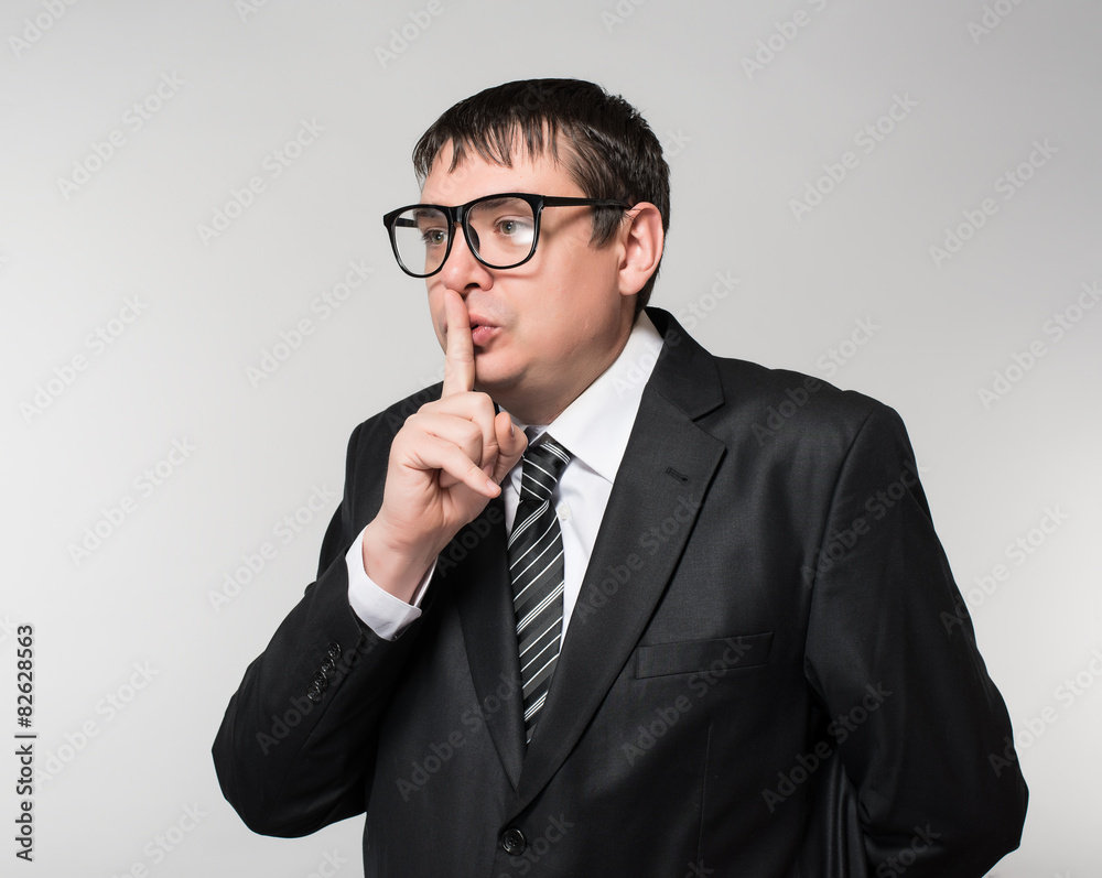 Young businessman in glasses shows quietly Young businessman in glasses shows quietly