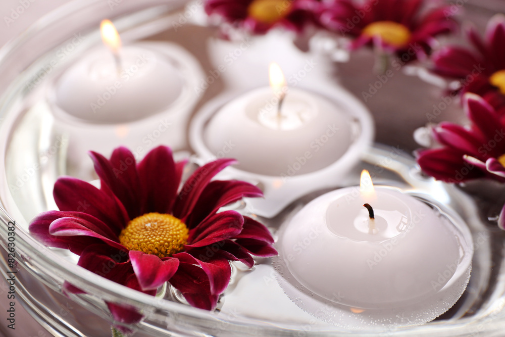 Bowl of spa water with flowers and candles, closeup Bowl of spa water with flowers and candles, closeup