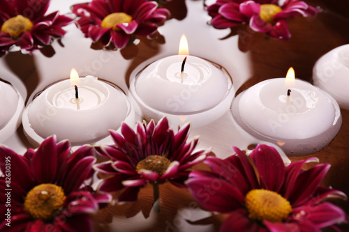 Bowl of spa water with flowers and candles, closeup