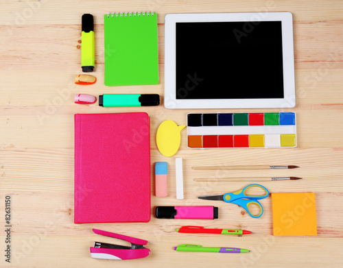 Digital tablet with stationery on wooden background