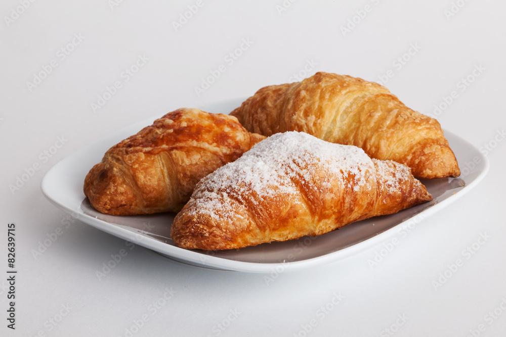 Three croissant on a plate white background