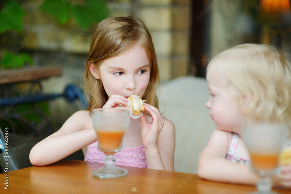 Two sisters drinking juice and eating pastries Two sisters drinking juice and eating pastries
