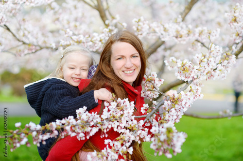 Mother and her child in blooming cherry garden