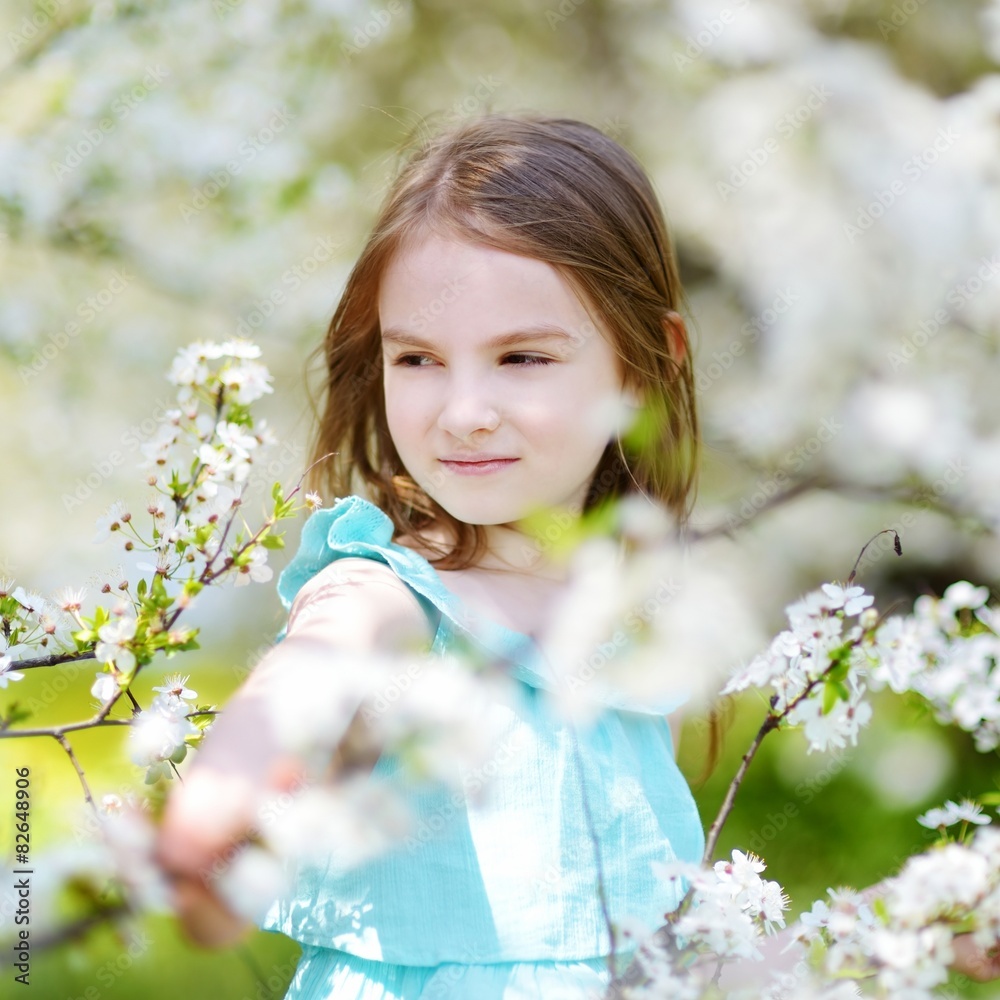 Adorable little girl in blooming cherry garden