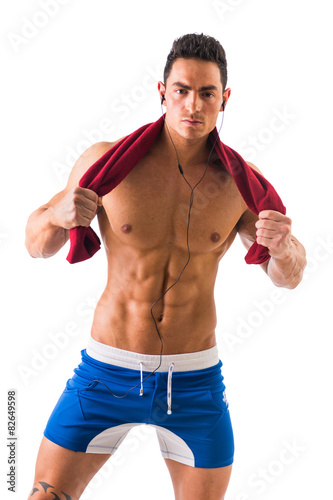 Handsome power athletic guy listening music & holding towel 