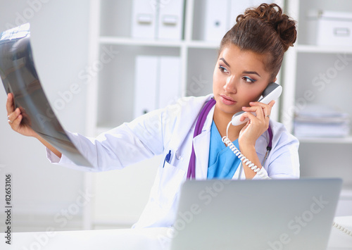 Female doctor looking x-ray scan and talking on phone in photo