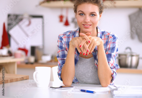 Young woman reading mgazine In kitchen at home photo