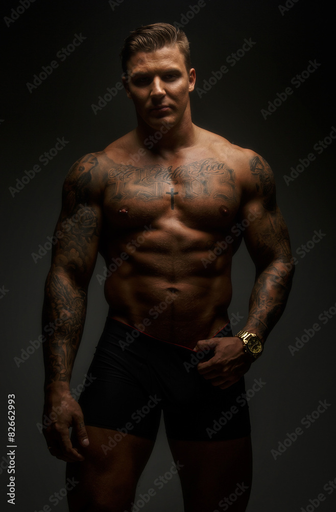 Muscular man with tattooes in deep shadows Muscular man with tattooes in deep shadows