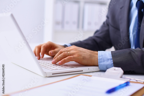Businessman sitting in office, working with laptop computer © lenetsnikolai
