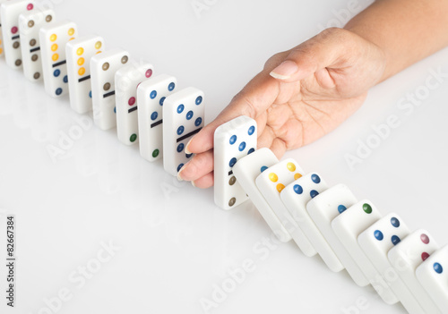 Hand stopping falling dominoes - domino effect