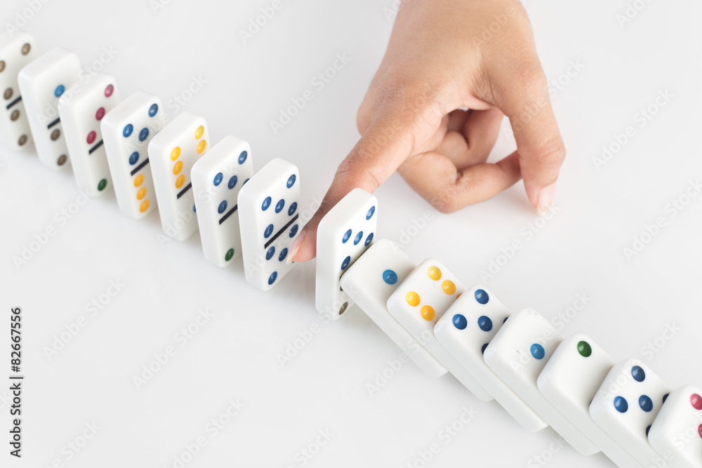 Person stopping the dominoes from falling - domino effect Person stopping the dominoes from falling - domino effect
