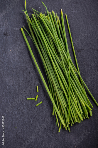 Spring garden fresh chives on black slate  background