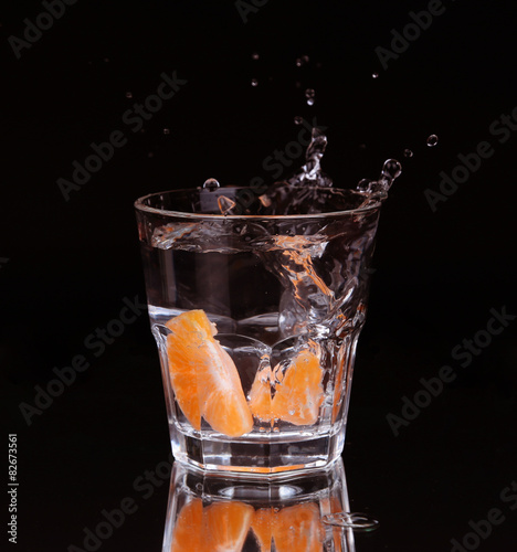 Slice of lemon splashing into a glass 