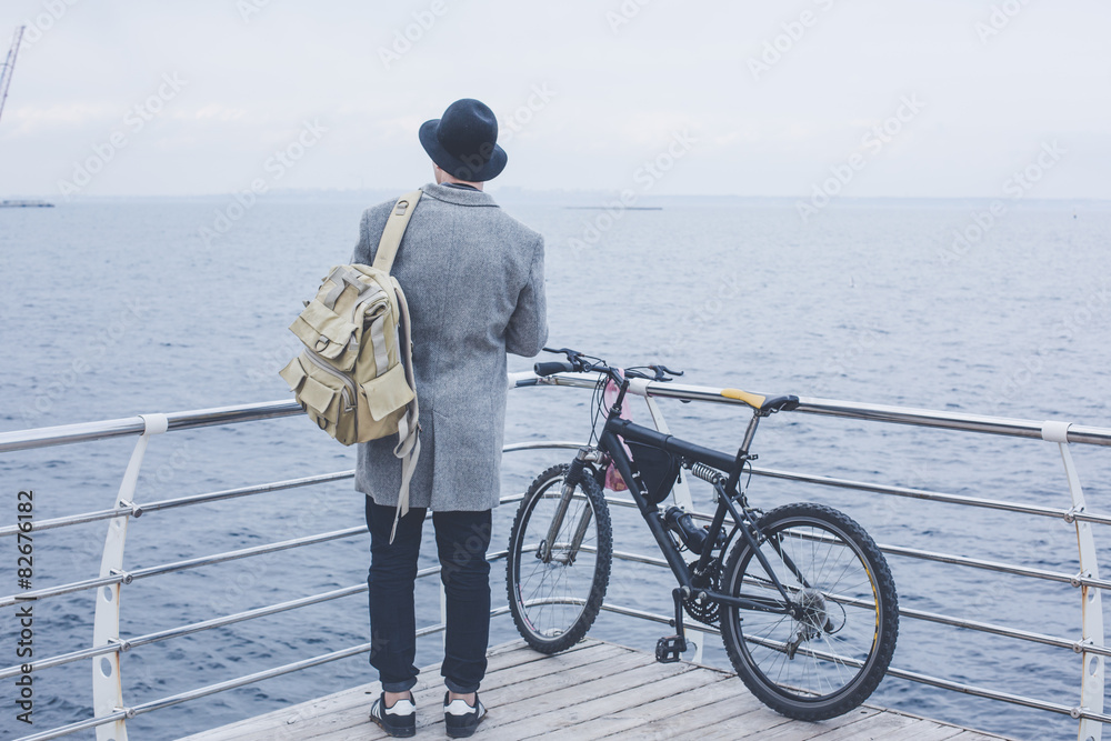 Obraz premium handsome young hipster guy in hat with bike looking at the sea