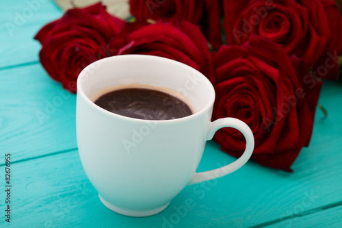 Espresso cup of Coffee and red roses on blue wooden table. Selective focus