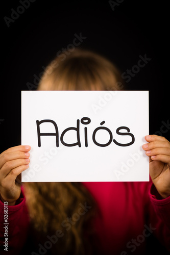 Child holding sign with Spanish word Adios - Goodbye