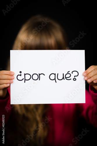 Child holding sign with Spanish words Por Que - Why