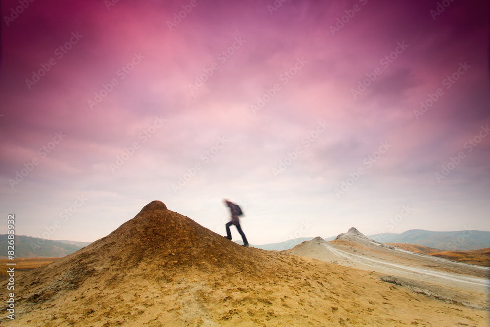Man climbing a hill with colorful clouds