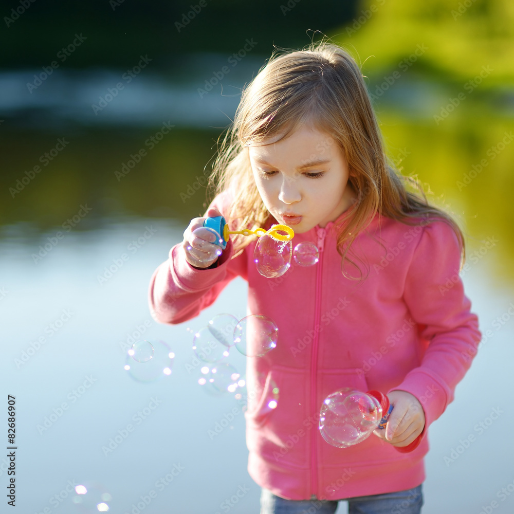 Funny lovely little girl blowing soap bubbles Funny lovely little girl blowing soap bubbles