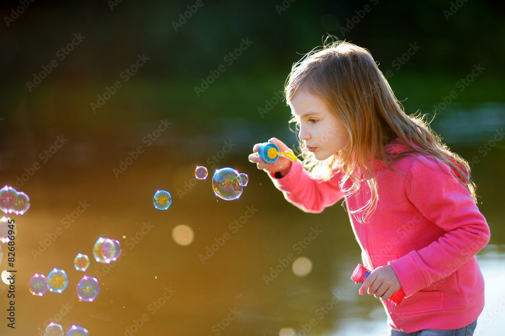 Funny lovely little girl blowing soap bubbles