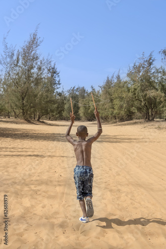 Afro boy running in the sand, ten years old  photo