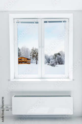 Wooden house covered  snow seen through the window