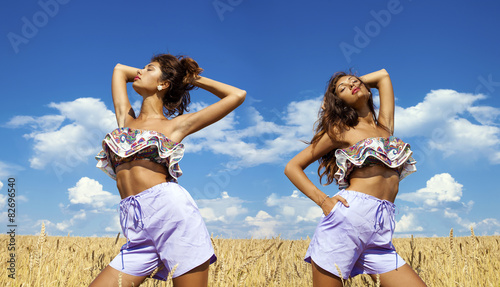Sexy young woman in blue shorts in a wheat golden field