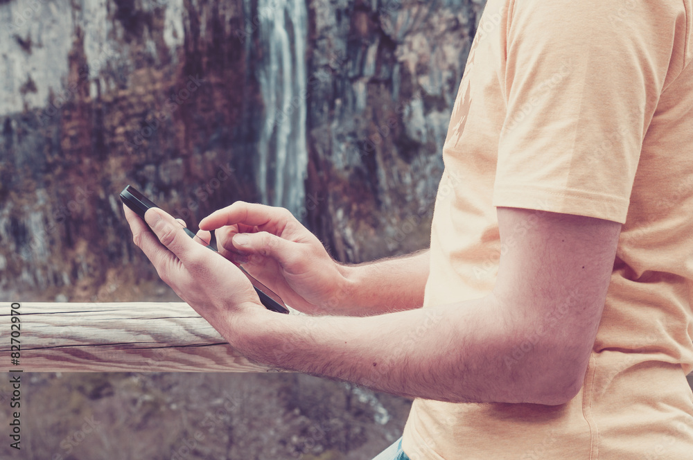 Man using a tablet. Natural setting, waterfall