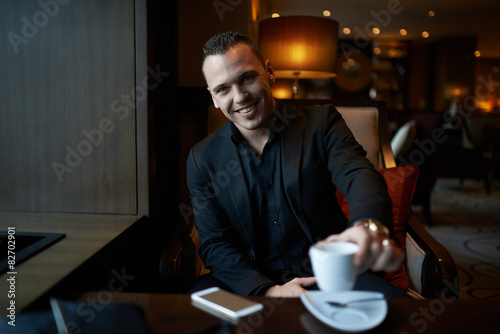 laughing businessman drinking coffee in restaurant