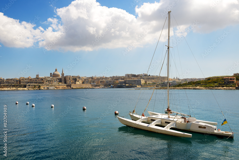 The view on Valletta and sail yacht with Ukrainian flag in sunse