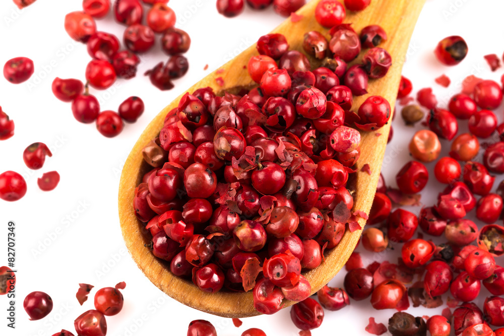 red peppercorns in wooden spoon isolated red peppercorns in wooden spoon isolated