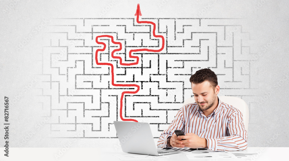 Business man at desk with labyrinth and arrow Business man at desk with labyrinth and arrow